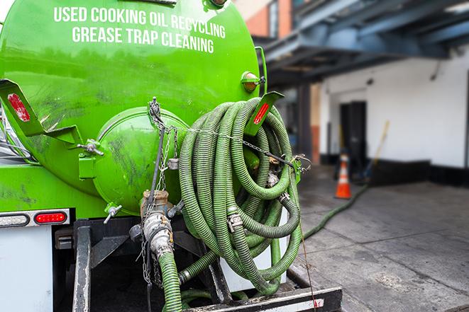 a grease trap being pumped by a sanitation technician in Bedford